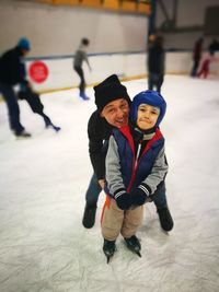 Portrait of man with son enjoying ice-skating