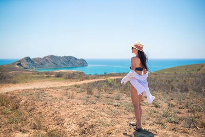 Rear view of woman standing on field against clear sky