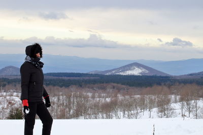 Woman standing on mountain against sky during winter