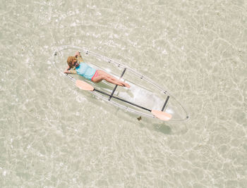 High angle view of girl relaxing in a transparent canoe in tropical waters