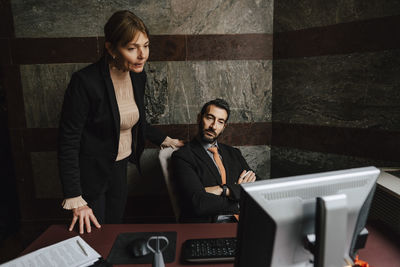 Businesswoman and businessman staring at computer monitor at law office