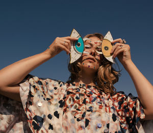 Portrait of woman holding hands against blue sky