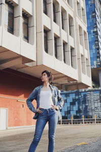 Young woman with hands on hip standing against building