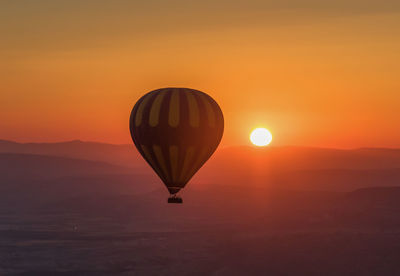 Hot air balloon flying against orange sky