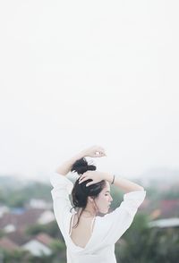 Woman standing with umbrella against clear sky