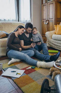 Parents with son using digital tablet while sitting in living room at home