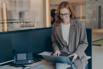 Young businesswoman using laptop while standing in office
