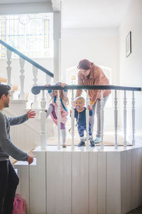 Father looking at playful family standing on steps