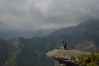 Man on rock against sky