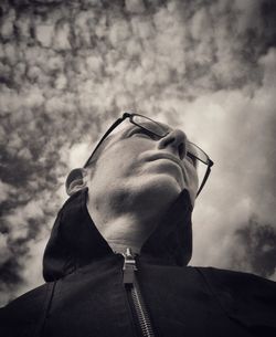 Low angle view of mature man wearing eyeglasses against cloudy sky