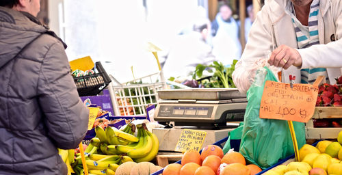 Midsection of customers buying fruits at market 