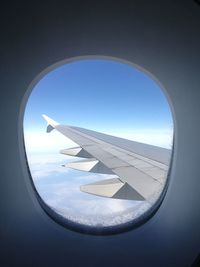 Aerial view of airplane wing against sky seen through window