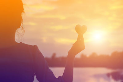 Silhouette woman standing by sea against sky during sunset