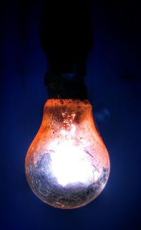 Close-up of illuminated light bulb against black background