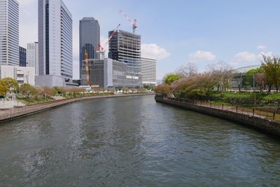 Bridge over river amidst buildings in city against sky