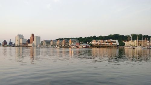 Scenic view of river by buildings against clear sky