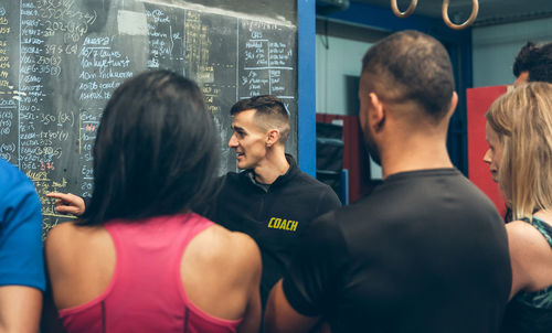 Instructor explaining over blackboard to athletes in gym