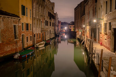 Canal amidst buildings in city at night