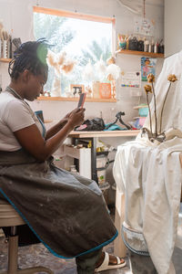 Female pottery artist business owner taking photos of her ceramics