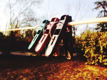 Close-up of clothespins hanging on clothesline against sky