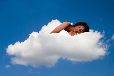 Low angle view of woman lying against blue sky