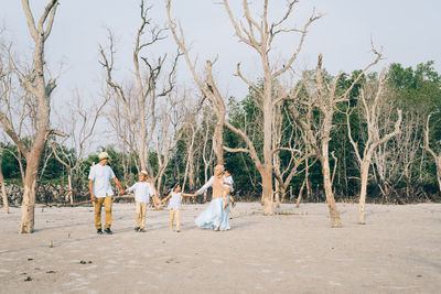 Family with holding hands walking against bare trees