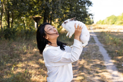 Side view of young woman with a bunny  walking in park
