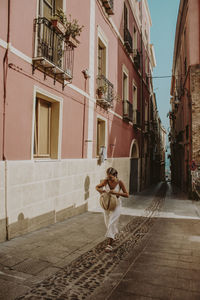 Woman walking at alley in city