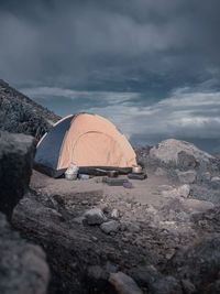 Tent on rocky shore against sky