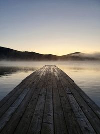 Pier over lake against sky during sunset