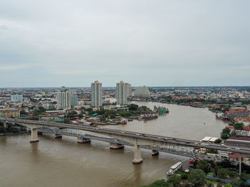 High angle view of bridge over river by buildings in city against sky