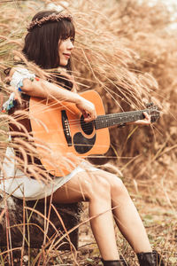 Young woman playing guitar on field