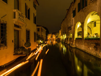 Illuminated street amidst buildings in city at night