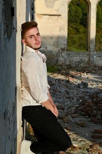 Portrait of young man standing against building