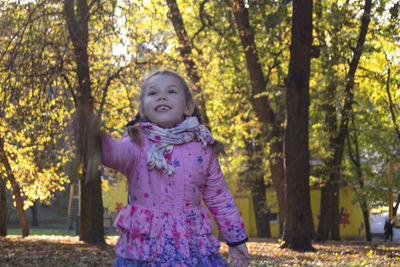 Portrait of cute girl standing by tree