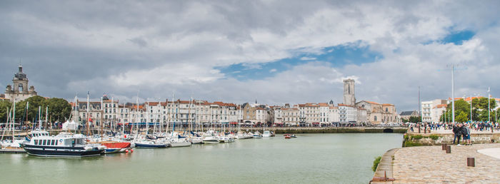 Sailboats moored in harbor against buildings in city