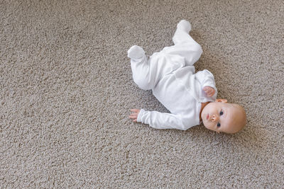 High angle view of baby girl lying on rug