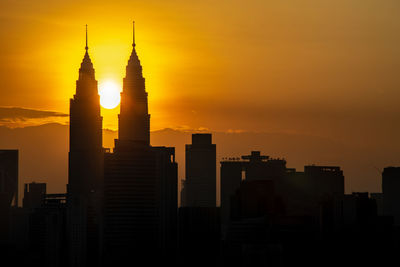 Silhouette of buildings in city during sunset