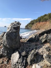 Rock formation on beach against sky