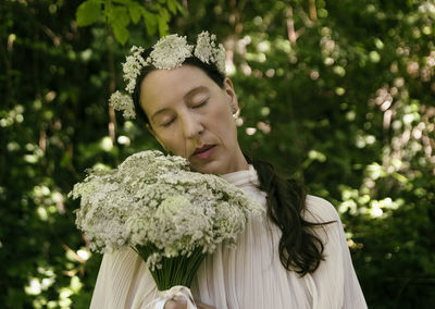 Woman in white blouse with flower bouquet and headband viii
