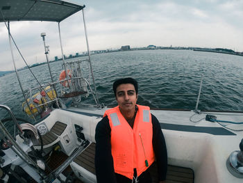 Portrait of young man standing in sea against sky