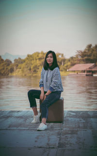 Portrait of woman sitting in water against sky