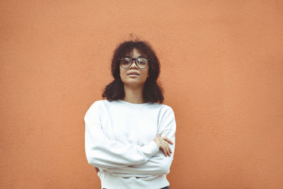 Portrait of young woman standing against yellow wall