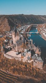 High angle view of castle and river in city against mountains