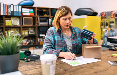 Woman entrepreneur checking return form of wrong package sent to client in online shop