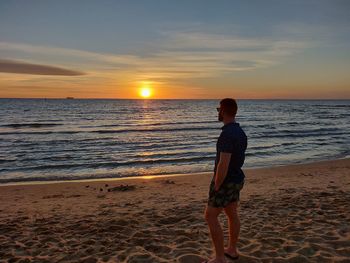 Full length of man standing on beach during sunset