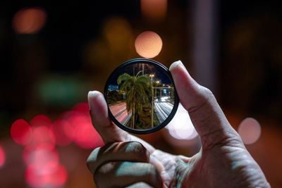 Close-up of hand holding mirror with reflection