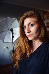 Portrait of model with brown hair standing by photographic umbrella at studio