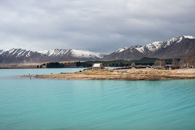 Scenic view of lake tekapo in morning with new zealand southern alps mountains against gloomy sky.