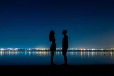 Silhouette men standing against blue sky at night